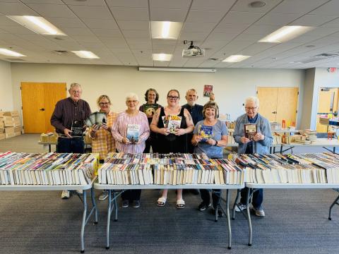 Friends members standing in front of books for sale